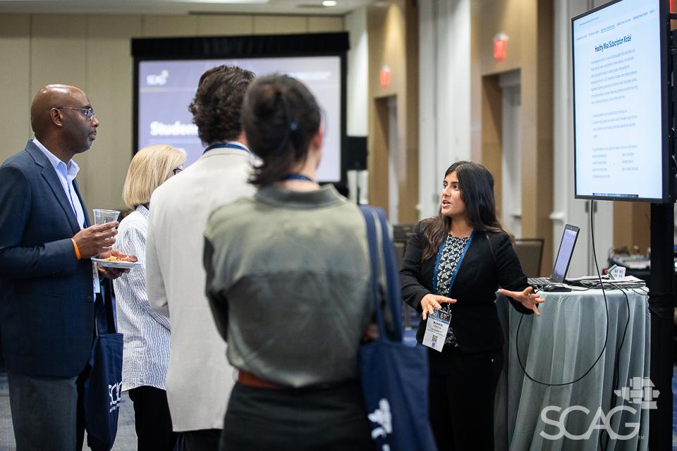 Group listening to presentation near large screen in conference setting.
