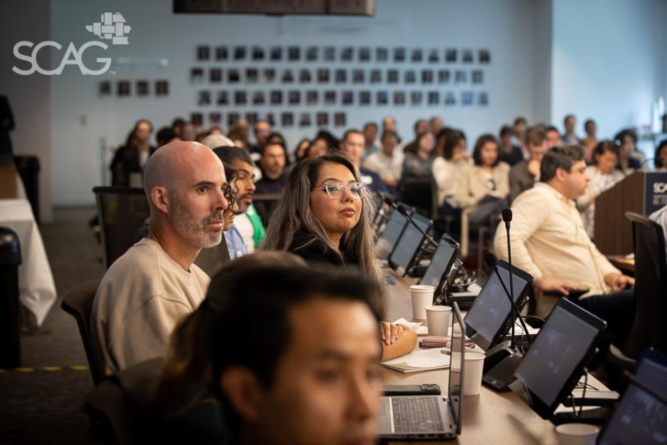 People seated in a conference room, focused on a presentation.