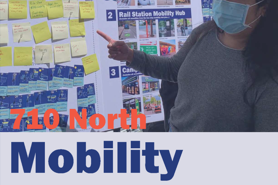 Person in a mask pointing to plans on mobility hub posters.