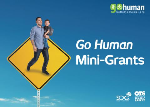 Man walking with child on yellow road sign, blue sky background.